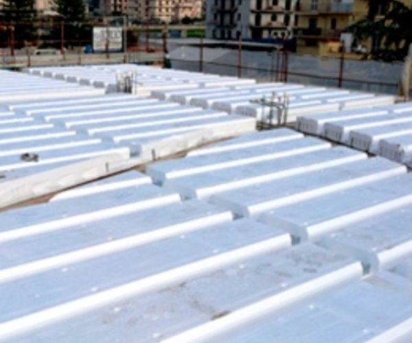 Tetto di un edificio in costruzione con pannelli isolanti bianchi del brand Bioisotherm, posizionati in file parallele, circondato da una struttura urbana. Soluzione efficiente per l'isolamento termico e acustico, ideale per migliorare l'efficienza energetica degli edifici.