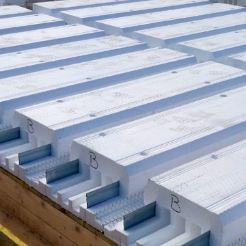 Pannelli di solaio Plastbau New Classic di Bioisotherm in EPS, disposti in fila su una struttura di legno. Leggeri e resistenti, offrono isolamento termico ed efficienza energetica, ideali per costruzioni sostenibili.