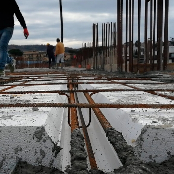 Vista ravvicinata di un cantiere con pannelli Plastbau di Bioisotherm in EPS. Si notano strutture in acciaio e cemento, evidenziando le caratteristiche di leggerezza e isolamento termico del sistema per solai, parte della linea Plastbau per costruzioni sostenibili.