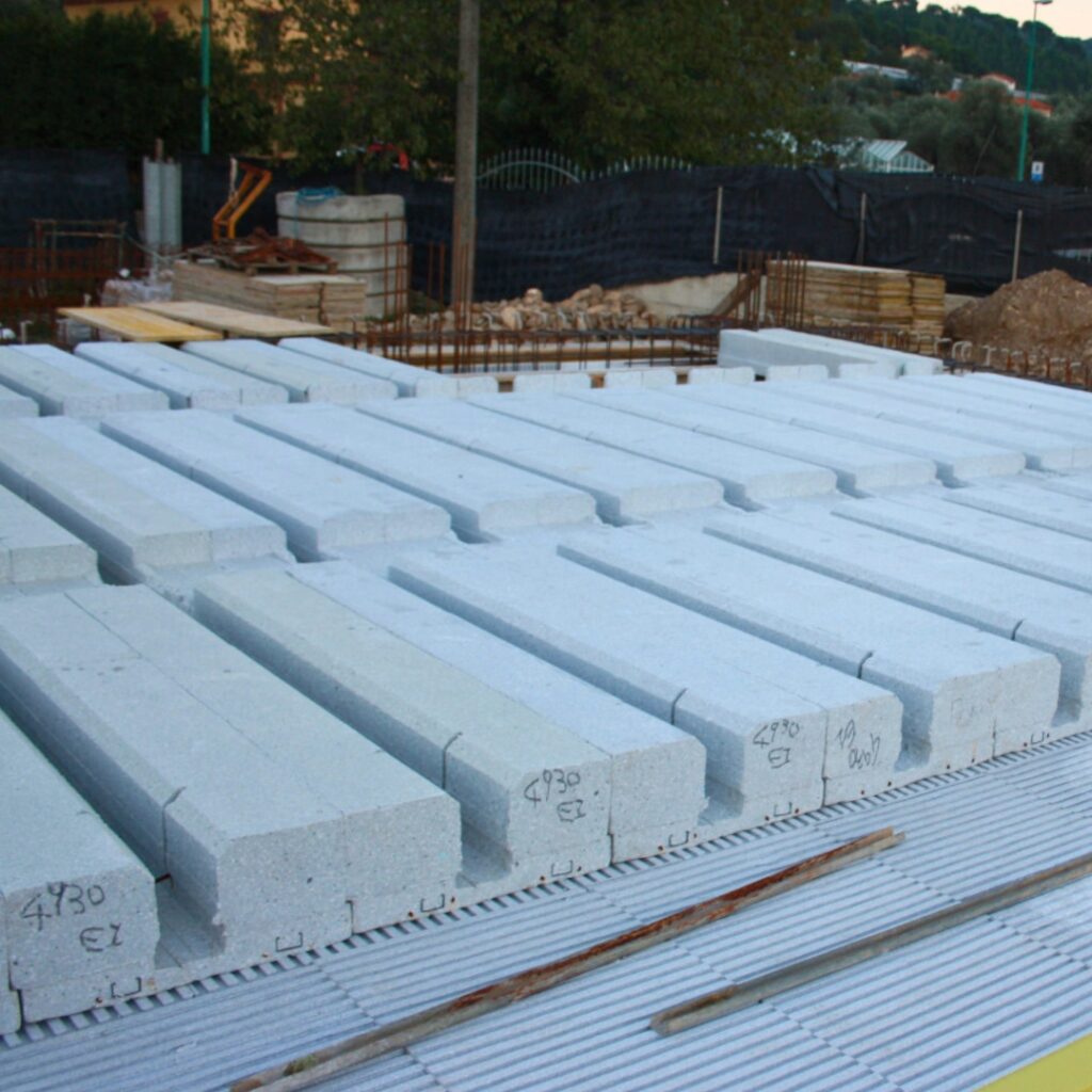 Blocchi di costruzione in calcestruzzo Bioisotherm disposti ordinatamente su un cantiere, pronti per l'installazione. Ideali per migliorare l'efficienza energetica e la sicurezza sismica delle seconde case, in linea con i bonus ristrutturazione 2025.